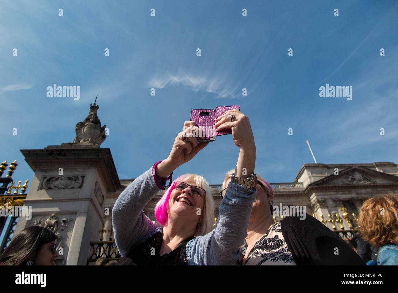 Two ladies with pink hair take a selfie and pictures of an event at Buckingham Palace Stock Photo