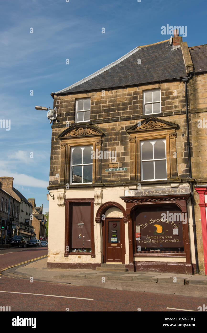 Historic corner building housing a chocolate shop on Bridge Street in a traditional British town, captured on a clear sunny day with blue sky overhead Stock Photo