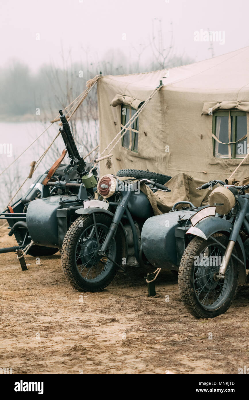 Old German motorcycles of gray color from the times of the Second World War with a machine gun mounted on the cradle are located at the military tent Stock Photo