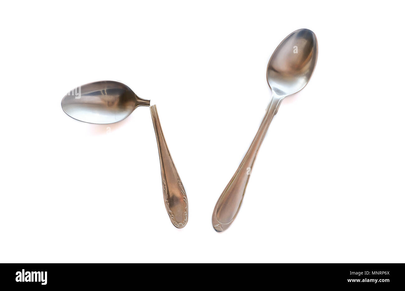 Two metal teaspoons - broken in half and serviceable on a white background. The concept of individuality in society and the family. Stock Photo