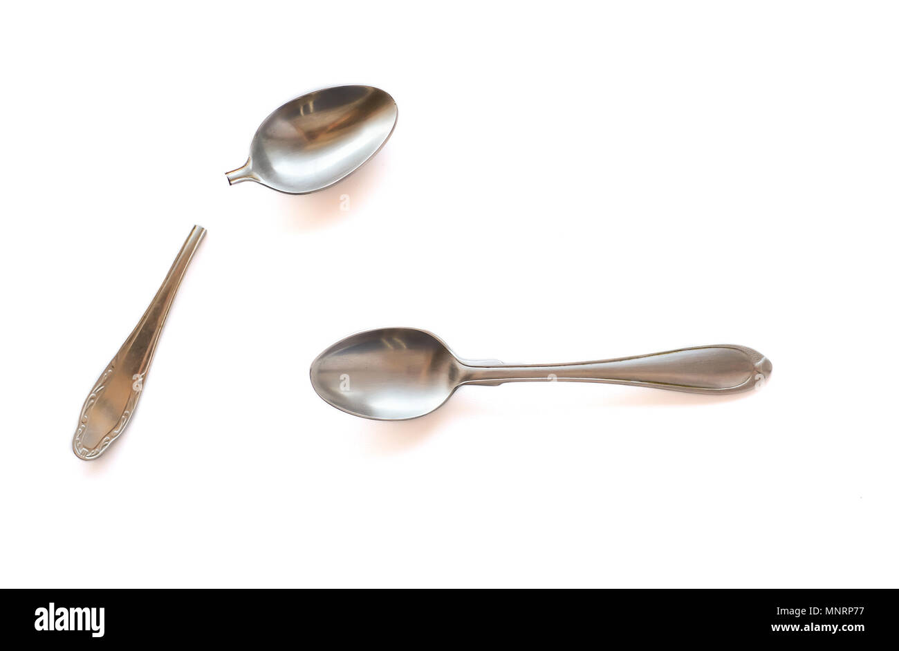 Two metal teaspoons - broken in half and serviceable on a white background. The concept of individuality in society and the family. Stock Photo