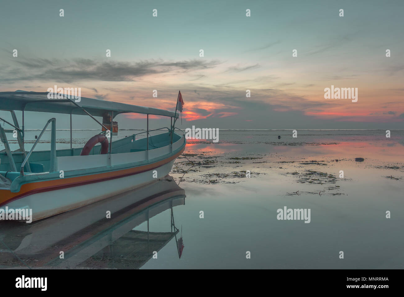 A small indonesian passenger boat at sunrise, reflections in the water, Sanur, Bali, Indonesia, April 21, 2018 Stock Photo
