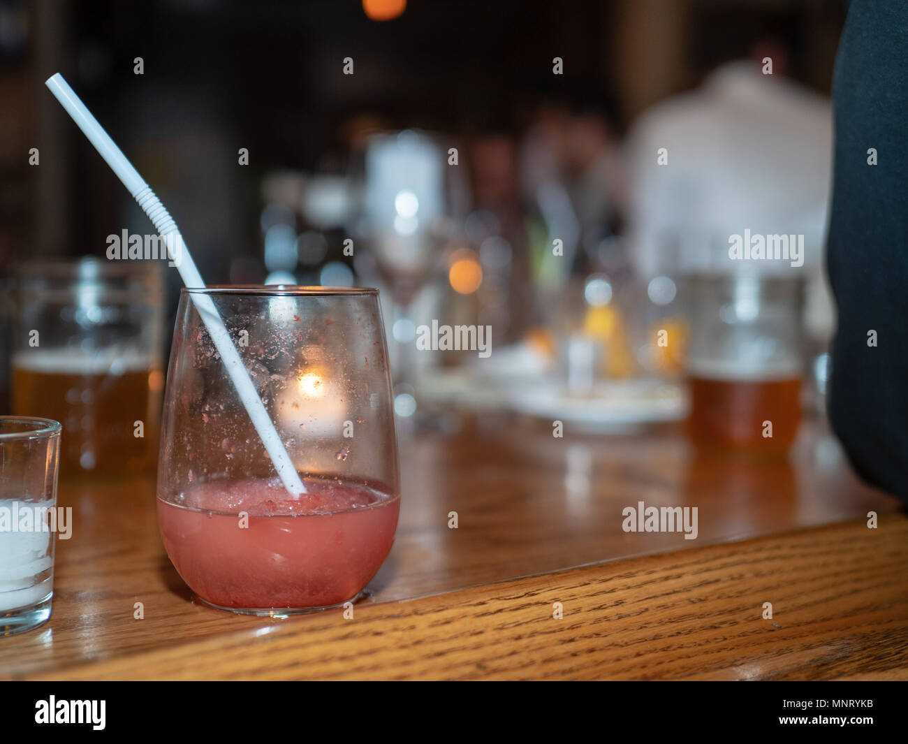 Fruity alcohol drink sitting on a busy bar with commotion all around