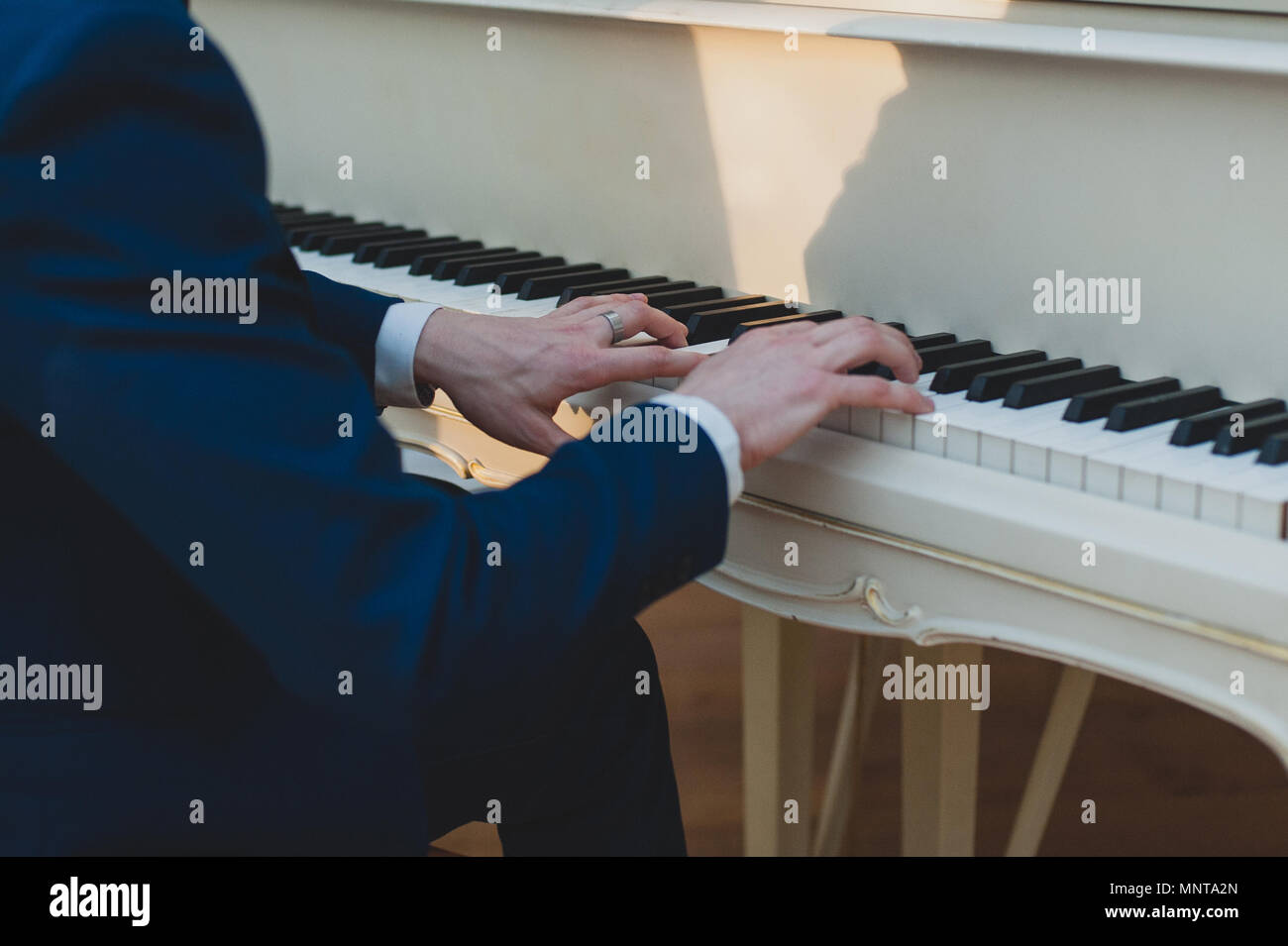 Pianist is playing on a white piano. Musical event, concert of classical music Stock Photo