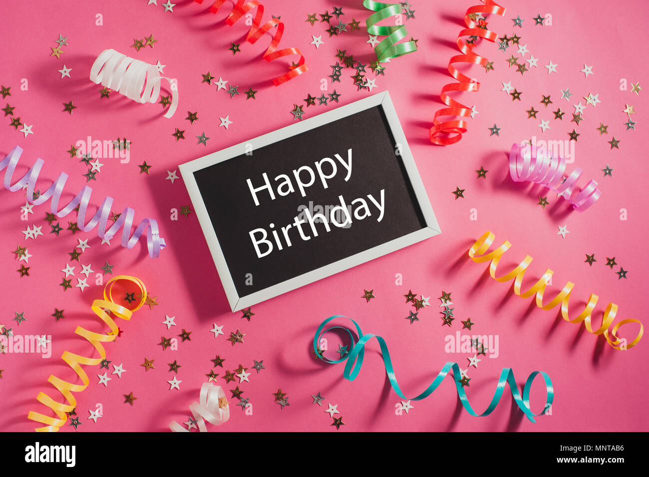 colorful party streamers gold little stars and blackboard with text