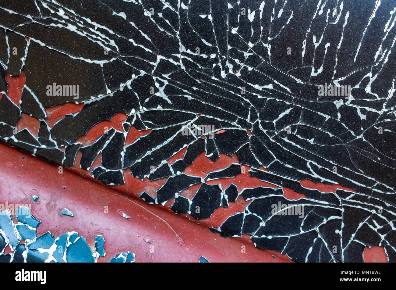 Cracked black paint on a vintage Bentley car, showing the red undercoat paint, London UK Stock Photo