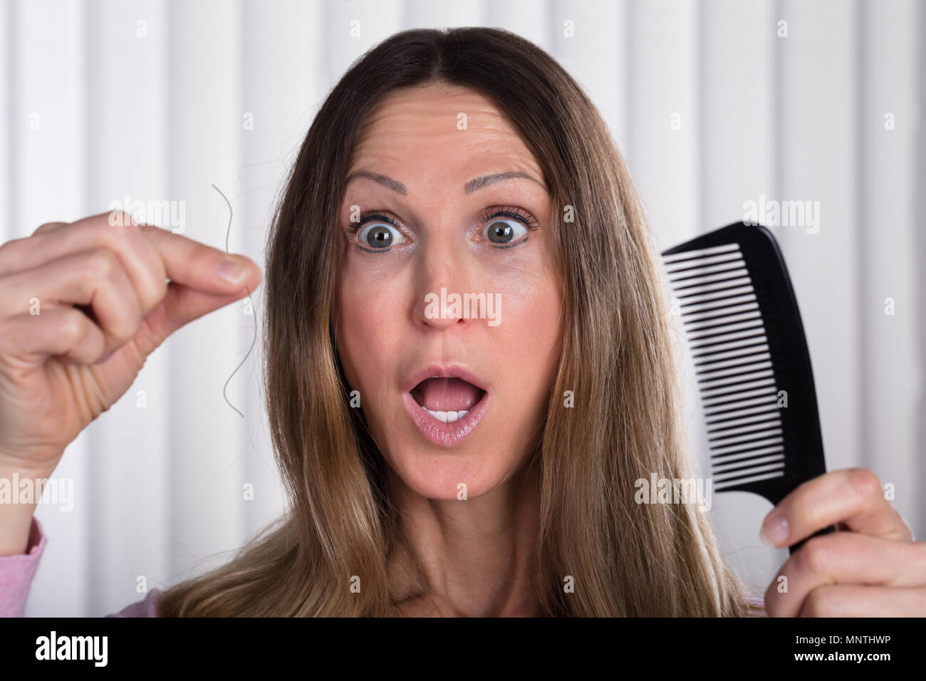 Shocked Woman Suffering From Hair Loss Problem Stock Photo
