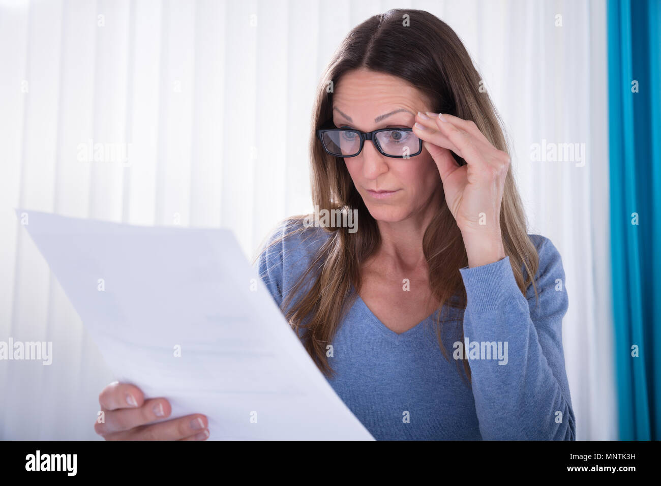 Close-up Of Mature Woman Wearing Eyeglasses Looking At Document Stock Photo