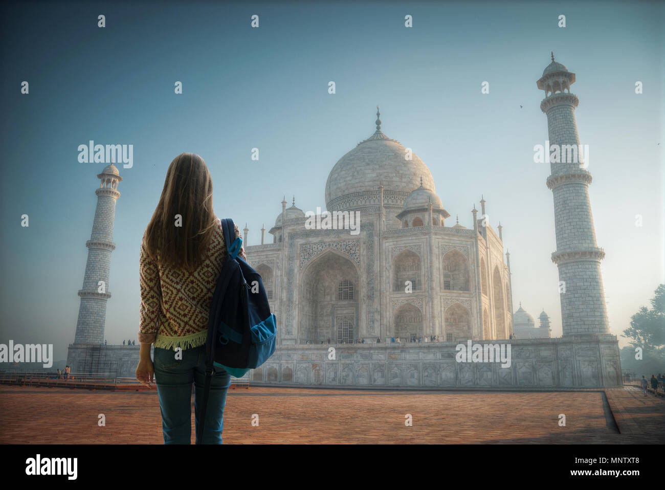 girl traveler stands with a backpack in the background of the Taj Mahal ...