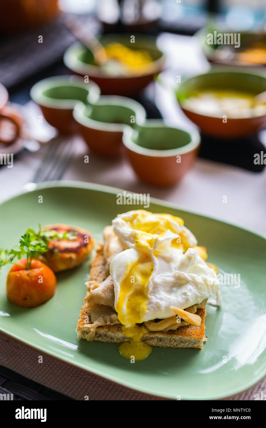 Breakfast table filled with assorted food. Poached eggs, Sri lankan curry and tea Stock Photo