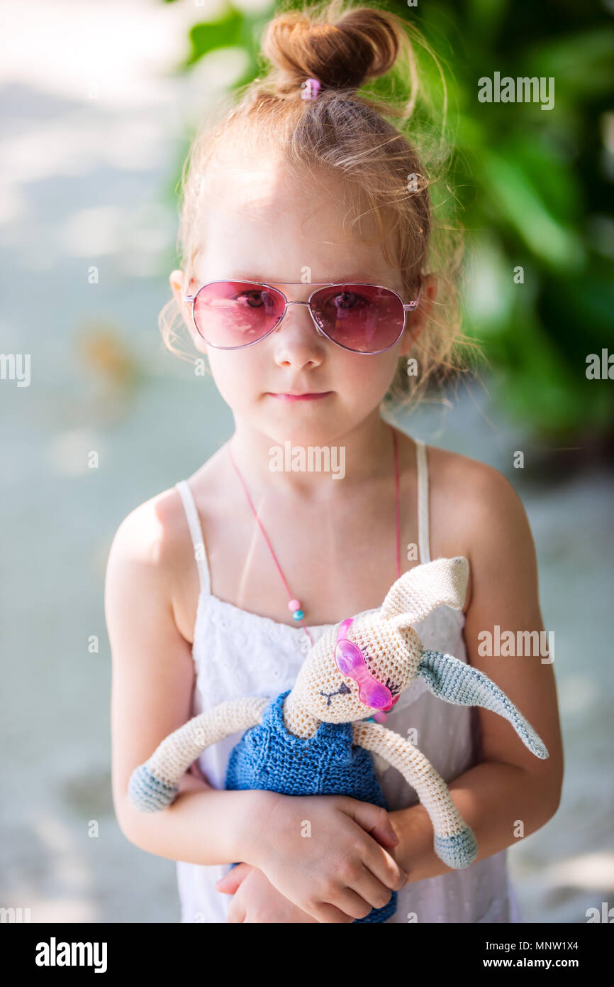 Little girl with a toy in pink sunglasses outdoors on summer day Stock