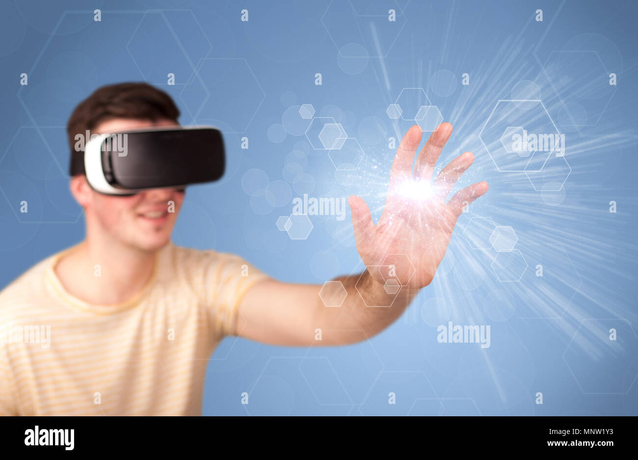 Young impressed man wearing virtual reality goggles with blue hexagons ...