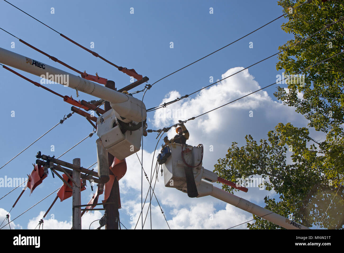 Workman using highlift bucket truck installing upgraded electrical service along a rural road in Vermont Stock Photo
