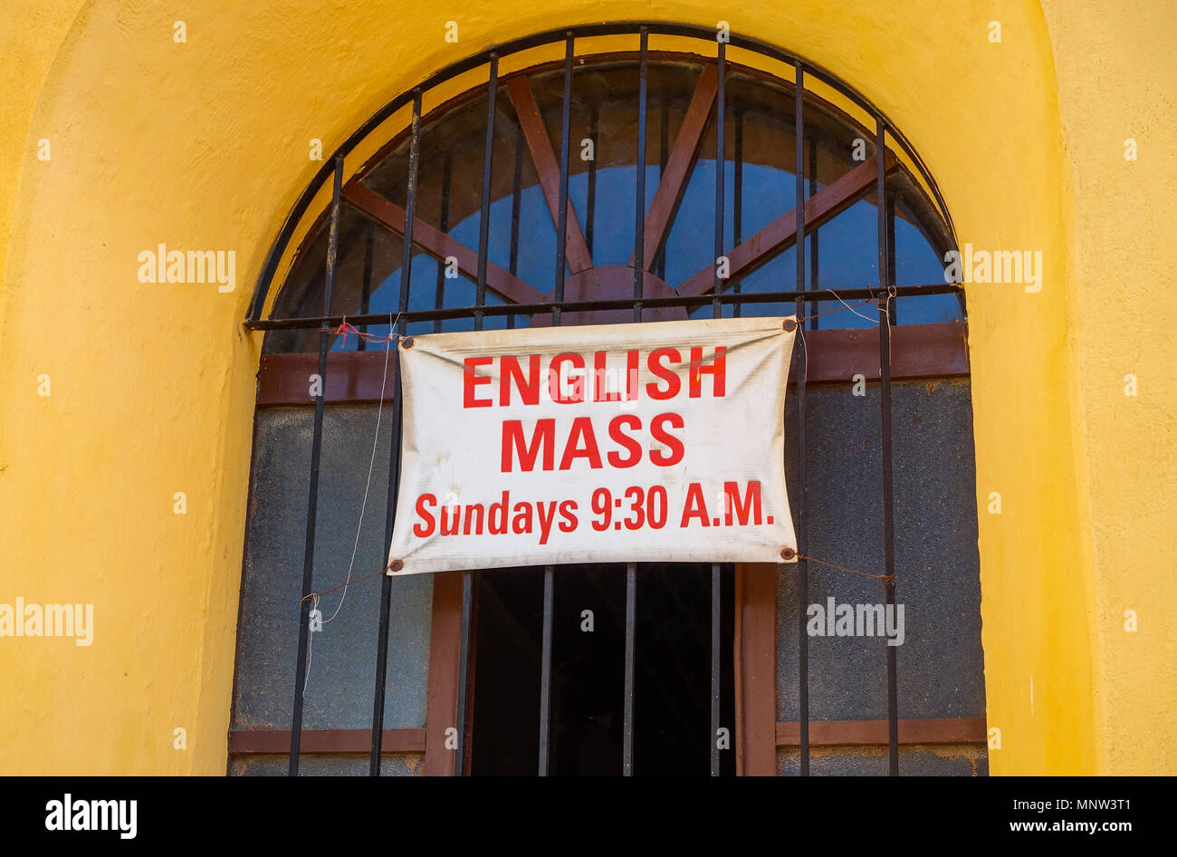 A sign in the window of a Catholic Church in San Miguel de Allende, Mexico announcing a mass in English Stock Photo