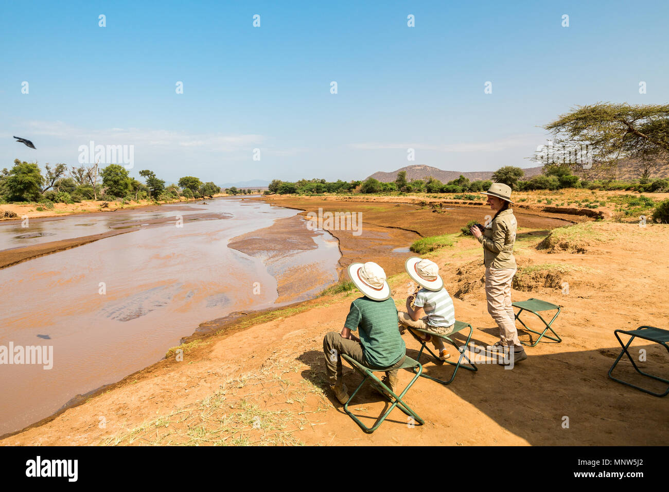Family of mother and kids on African safari vacation enjoying Ewaso Nyiro River views in Samburu Kenya Stock Photo