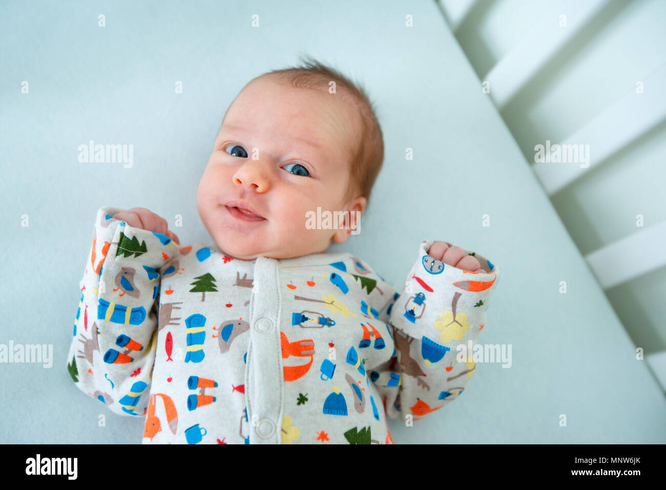 Cute newborn baby girl lying in cradle. Two weeks old infant child on white soft blanket Stock Photo