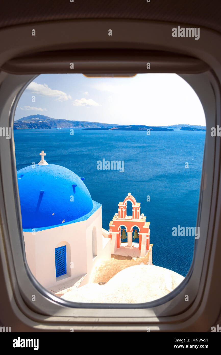 Oia town on Santorini island, Greece. Traditional and famous houses and churches with blue domes over the Caldera, Aegean sea through a frame of plane Stock Photo