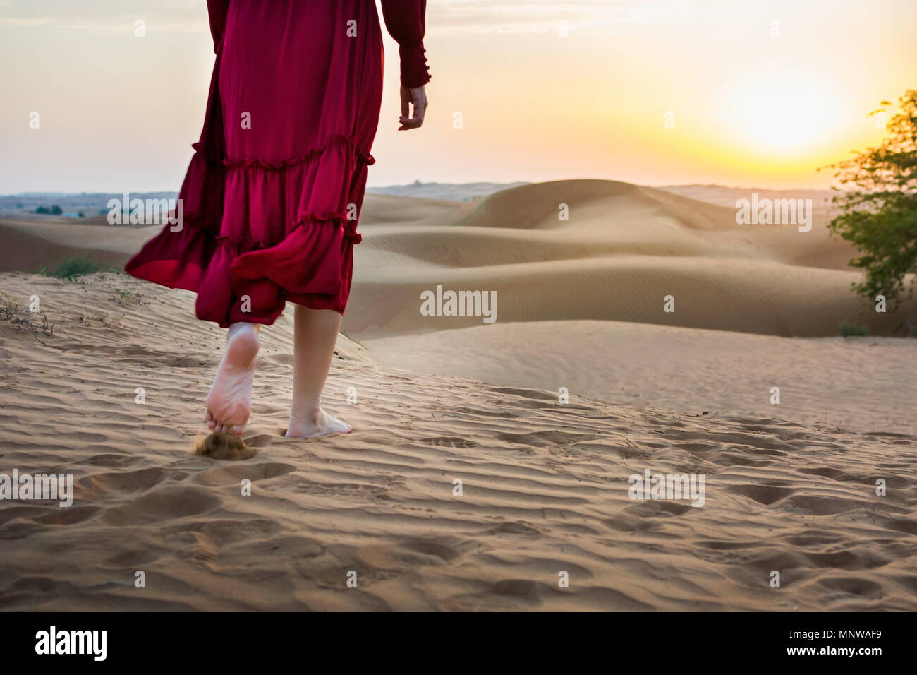 Woman walking in the desert at sunset back view Stock Photo