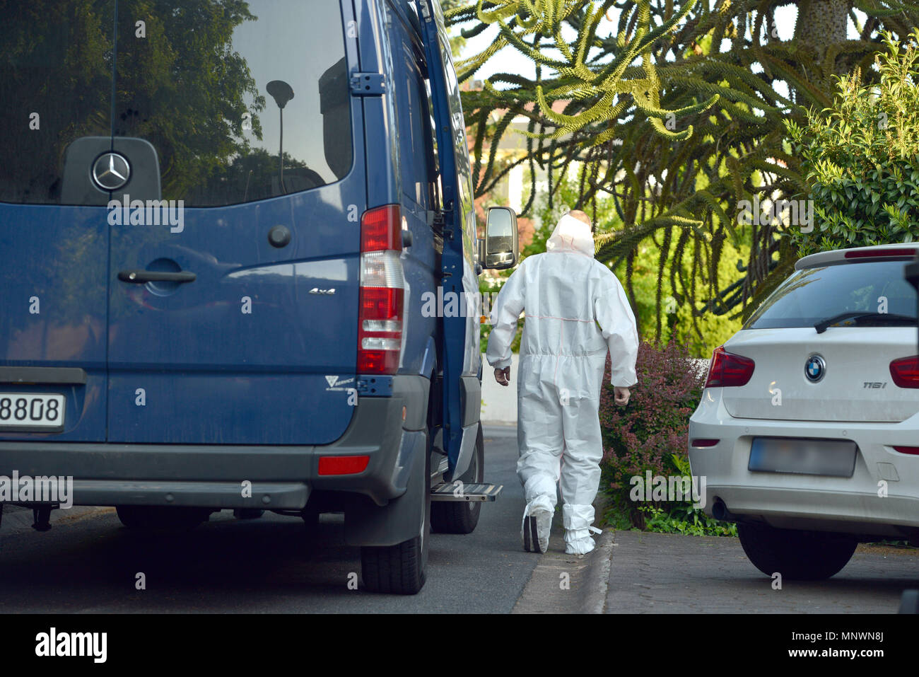 19 May 2018, Germany, Saarbruecken: A crime scene investigator walks past an unmarked police van. In a neighbouring house a man shot and killed to men and injured two women, according to police reports. Police also stated that an alleged suspect was arrested. (NOTE: The licence plate of the car (R) was pixelised for reasons of personal rights) Photo: Harald Tittel/dpa Stock Photo