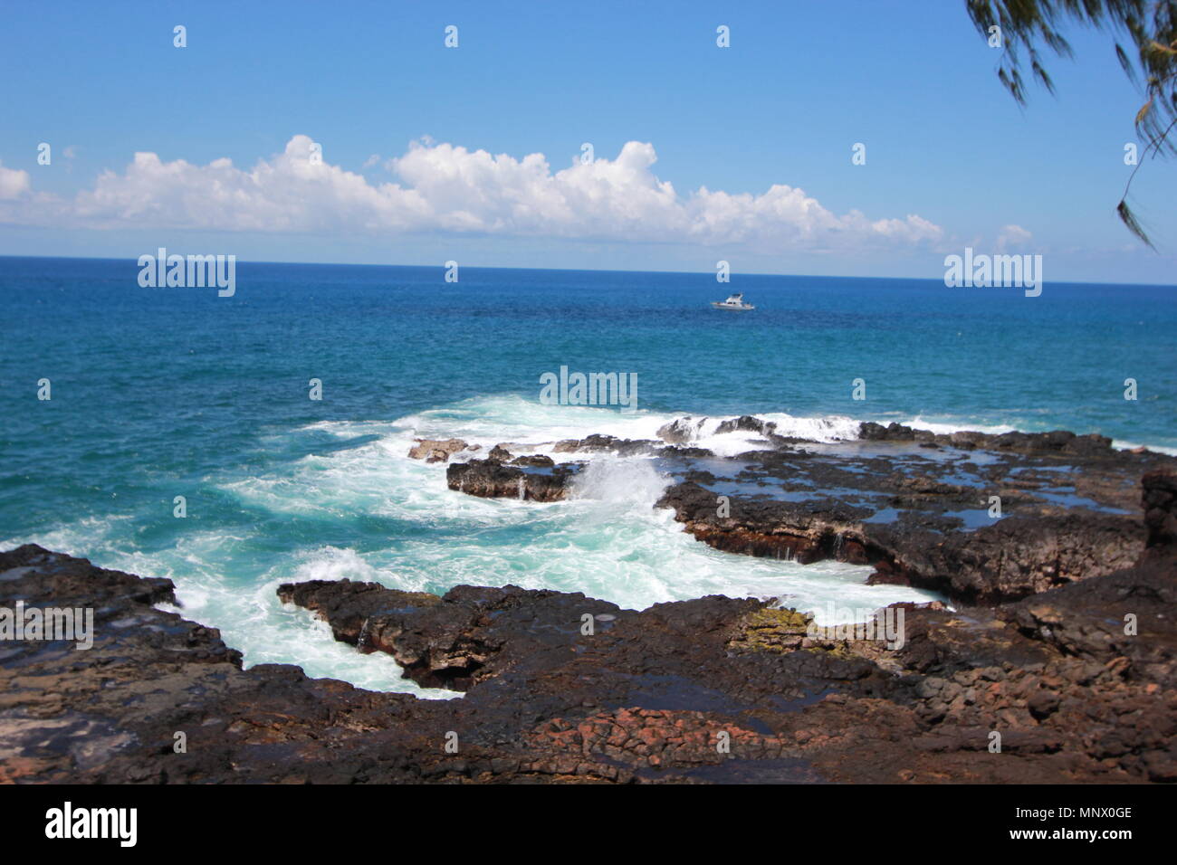 Spouting Horn is off the southern coast of Kauai in the Koloa district and is known for its crashing waves and large spray of water. Stock Photo