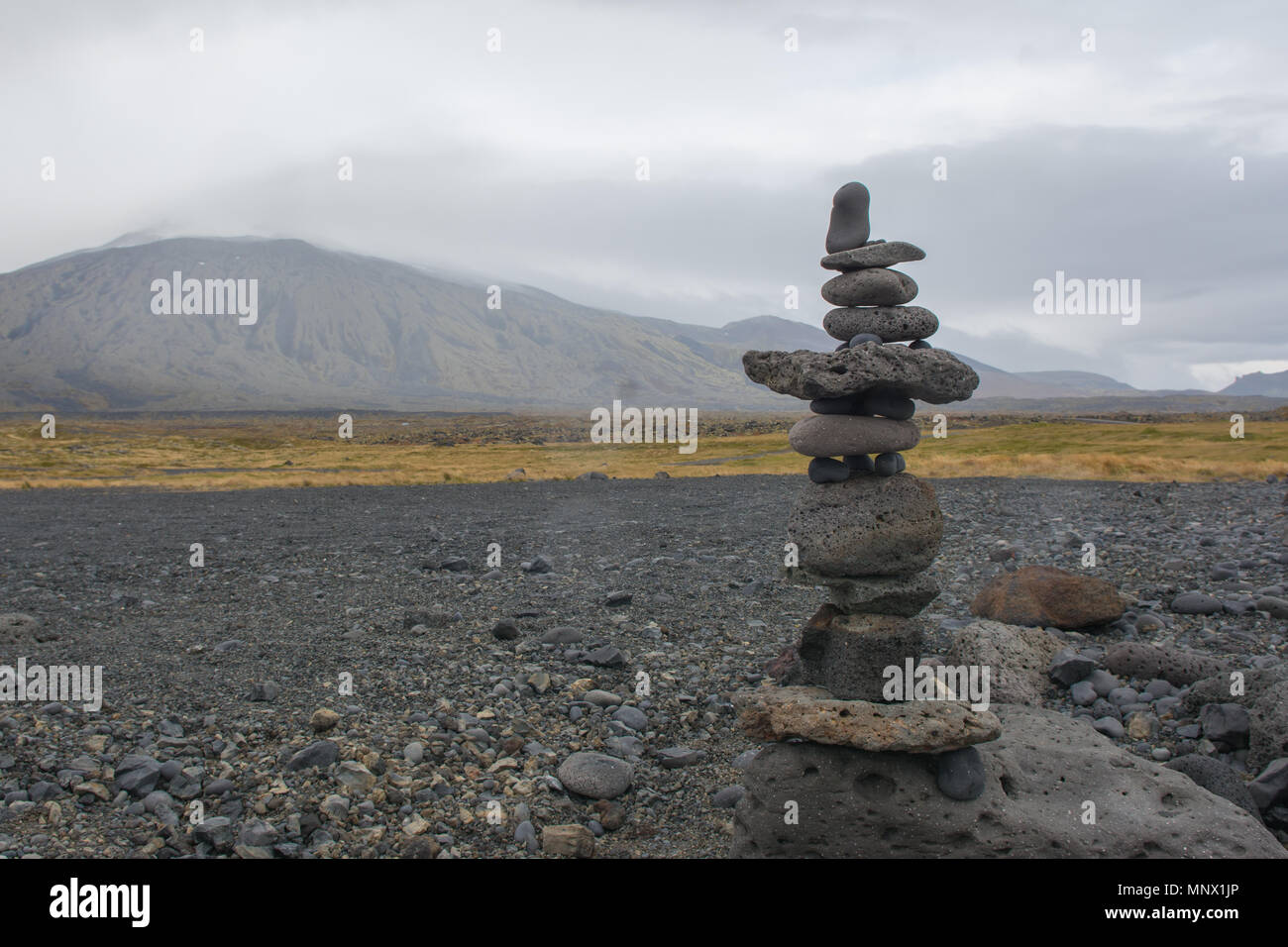 Rock stacking on rocky beach with mountains in background Stock Photo ...