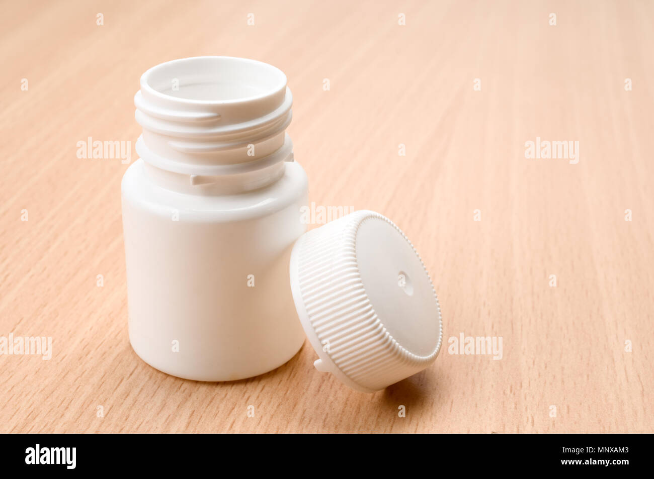 Empty plastic pill bottle on wooden table. Selective focus. Stock Photo