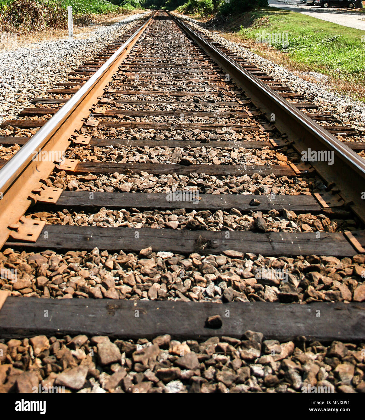 Railroad tracks through rural setting converging on vanishing point