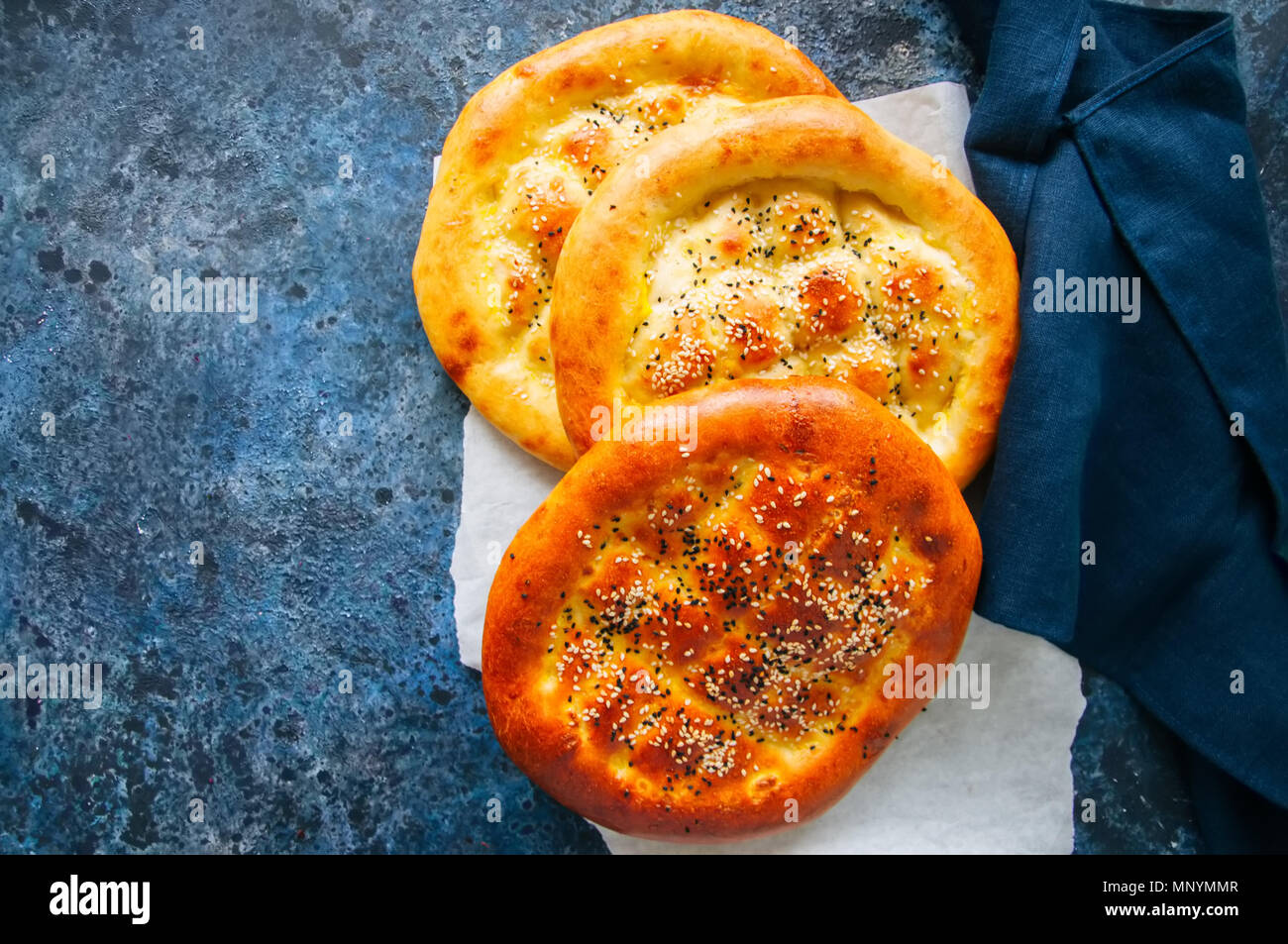 Turkish ramazan pidesi - Traditional Turkish ramadan flatbreads usually baked during ramadan month. Blue stone background. Top view. Stock Photo
