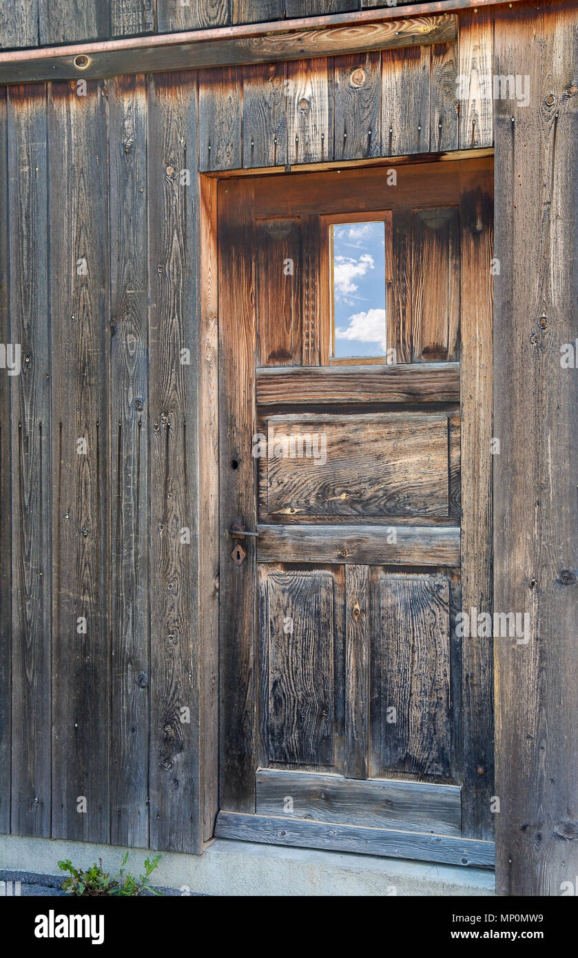 weathered old wooden door with sky reflection in window Stock Photo
