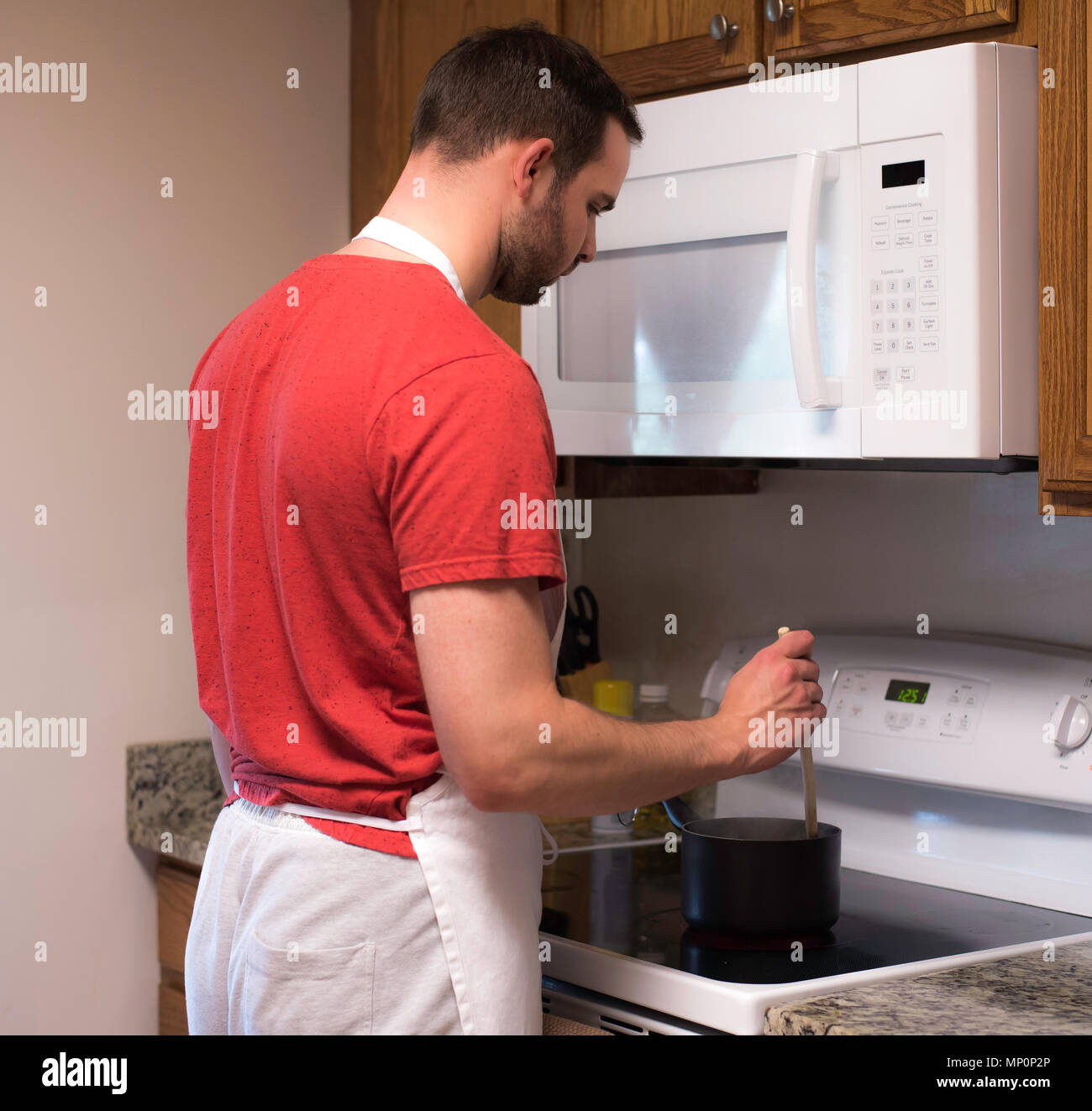 Handsome man stirring sauce in the kitchen at home Stock Photo