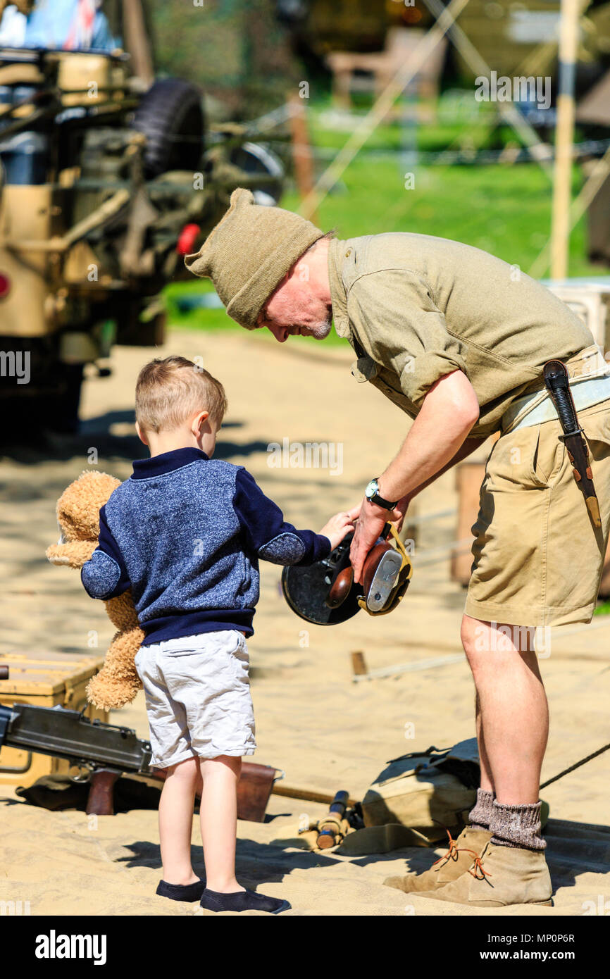 Salute to the 40s popular event in England. Member of the Desert Rats group showing a young boy, 3-5 years old, how to hold a tommy gun. Outdoors. Stock Photo