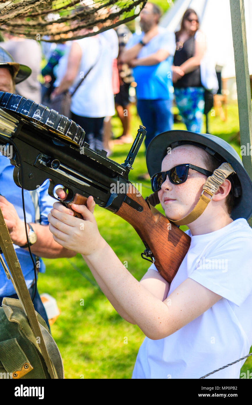 Salute to the 40s re-enactment event. Man dressed as world war two air-warden spotting for young freckle faced boy who is manning a Lewis aircraft gun Stock Photo