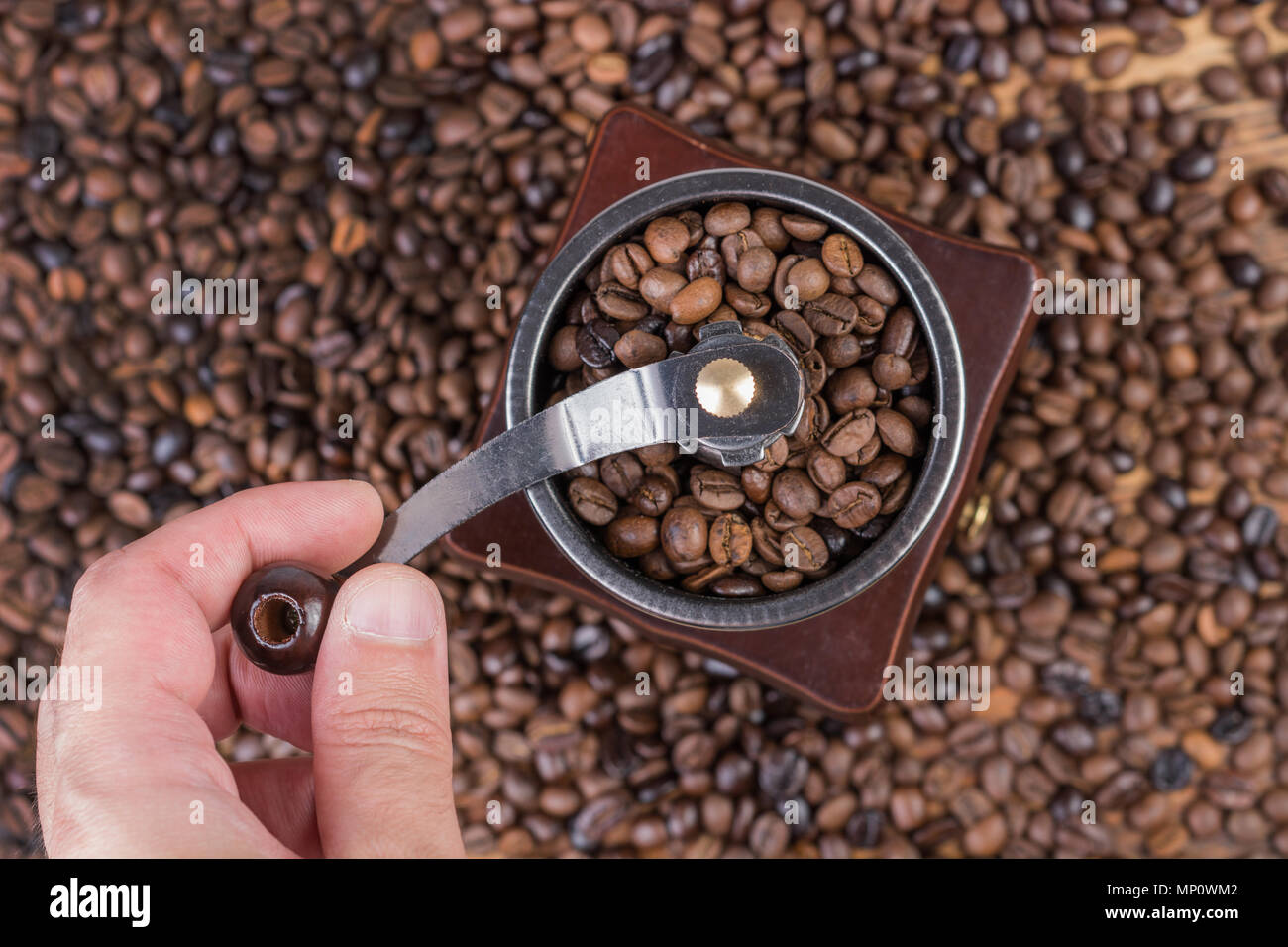 Male hand grinding coffee beans in old 