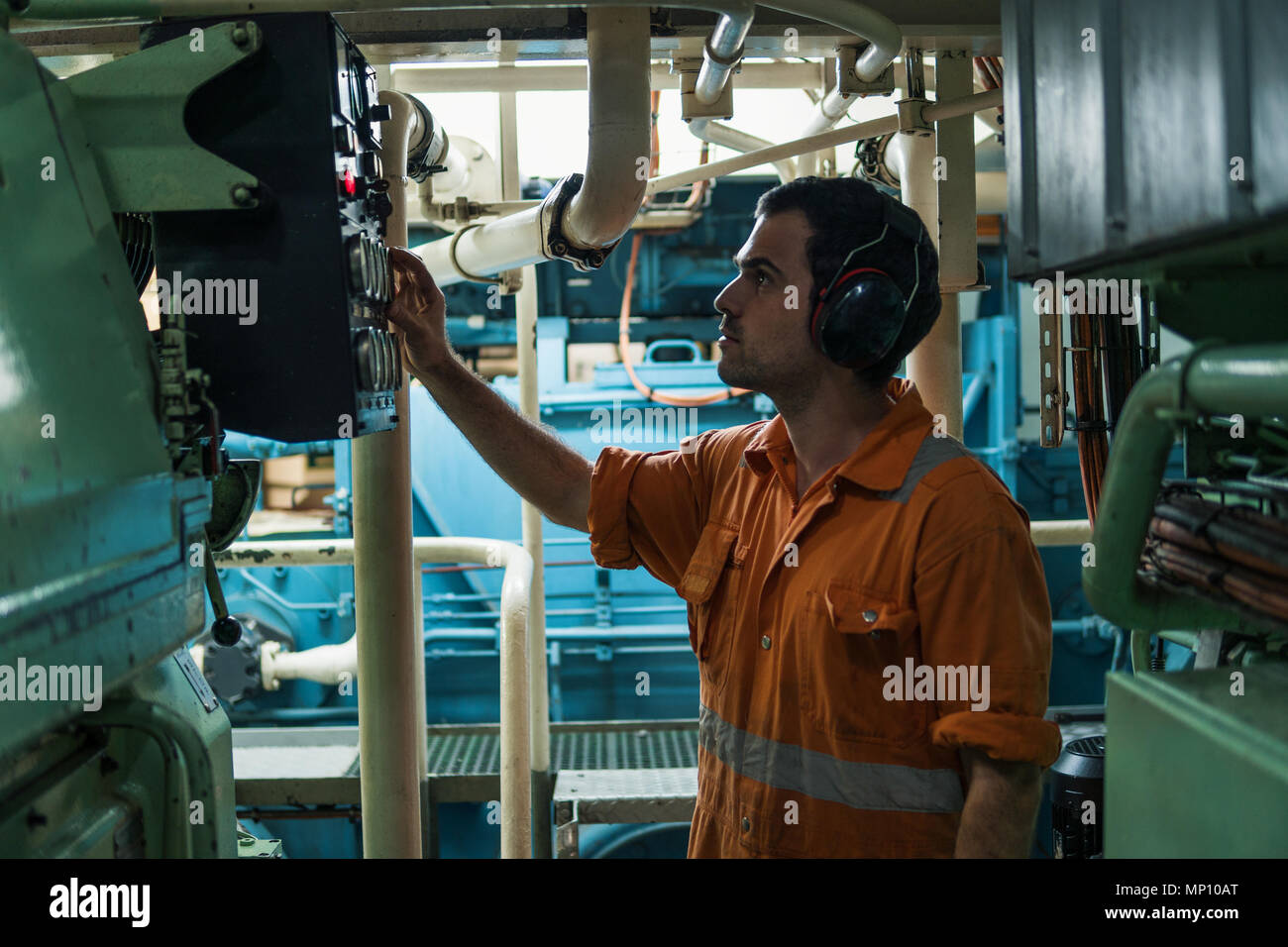 Marine engineer inspecting ship's engine in engine control room Stock