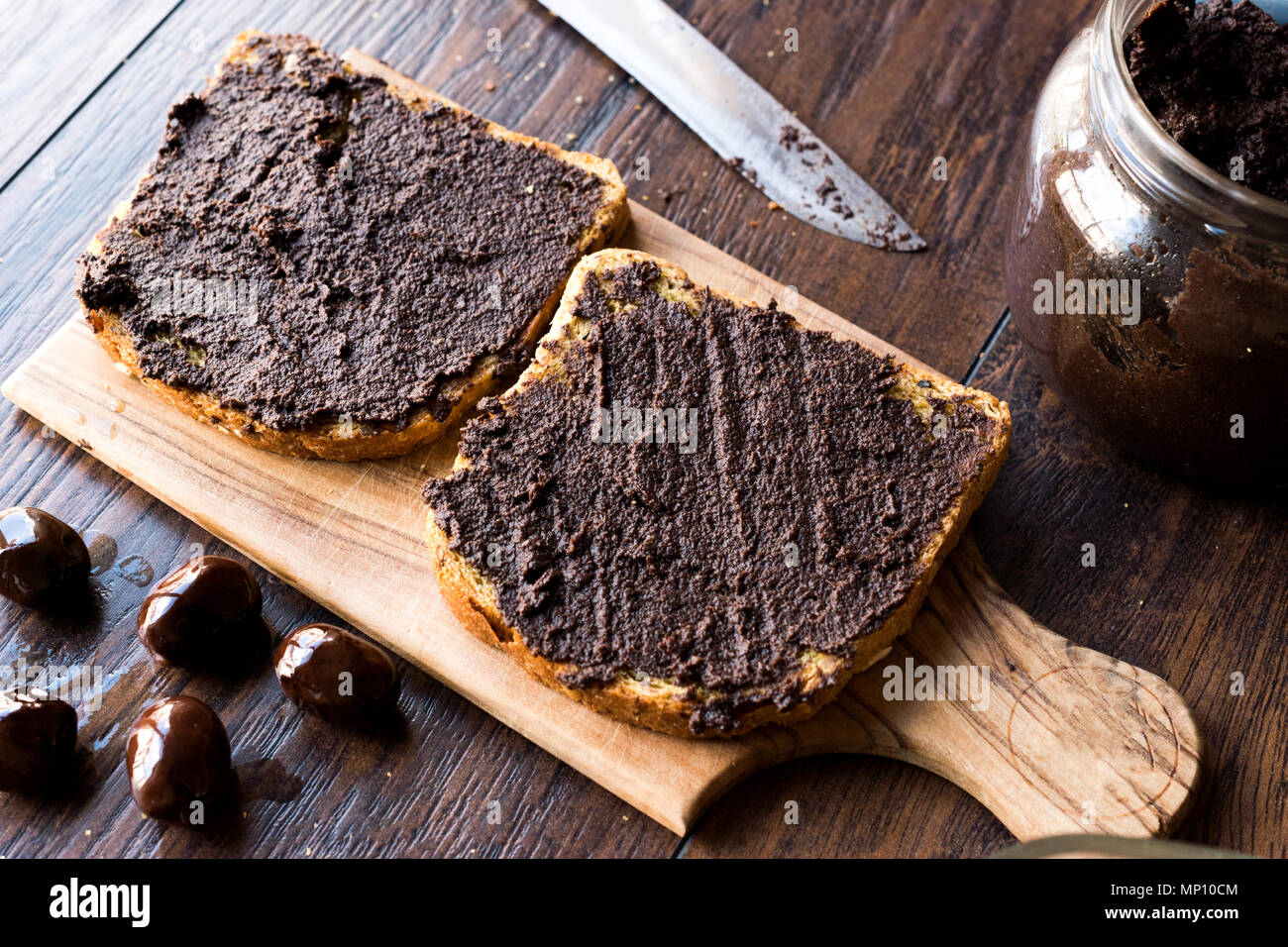 Black Olive Tapenade on Bread with Knife and Jar. Organic Food. Stock Photo