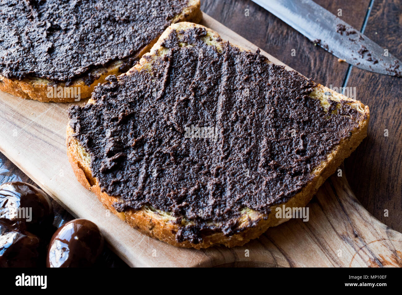 Black Olive Tapenade on Bread with Knife and Jar. Organic Food. Stock Photo