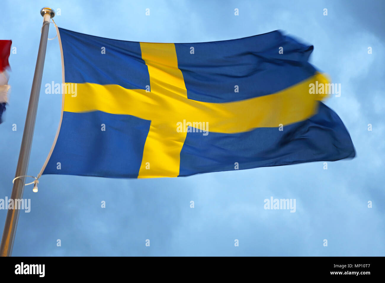 Sweden Blue Flag With Scandinavian Yellow Cross at Windy Night Stock Photo
