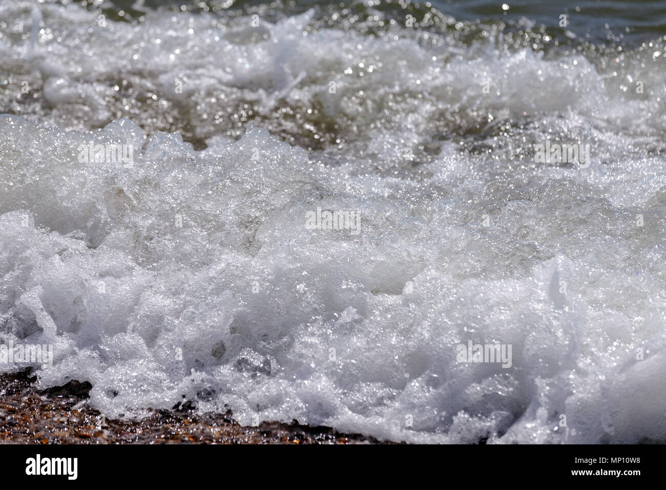 Sea waves landing on the coast of a shingle beach in the United Kingdom. Stock Photo