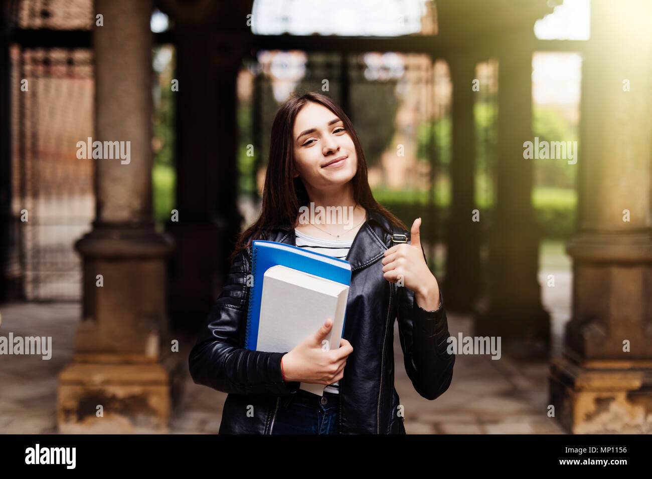 Portrait of a smiling female student showing thumb up outdoors Stock ...