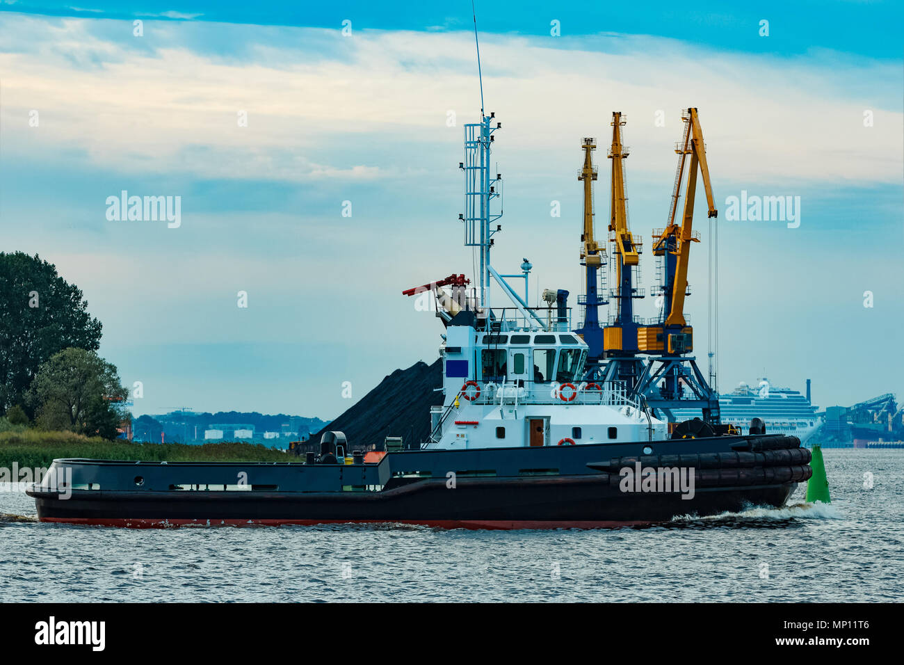 Black tug ship moving to the cargo terminal. Industrial service Stock