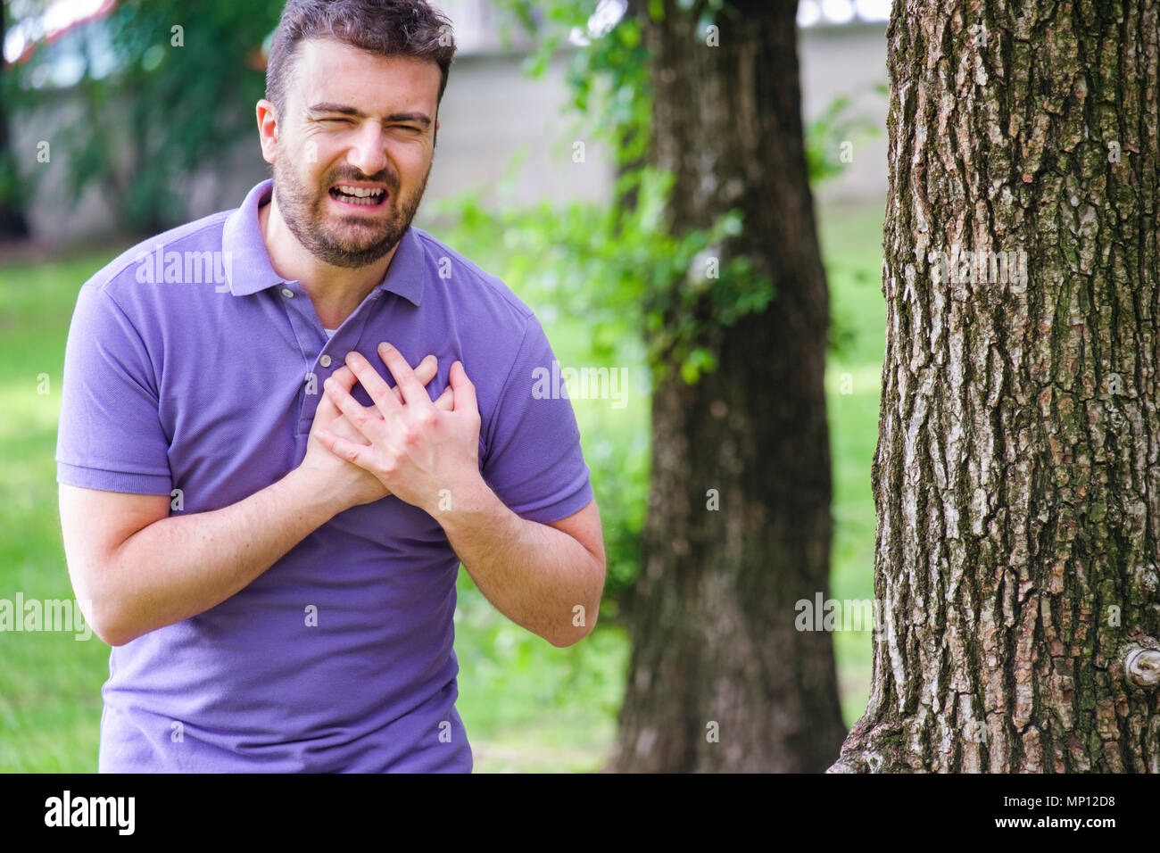 Severe heartache.Man pressing on chest with painful expression fist aid needed. Stock Photo