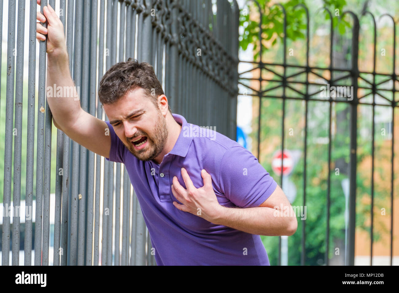 Severe heartache.Man pressing on chest with painful expression fist aid needed. Stock Photo