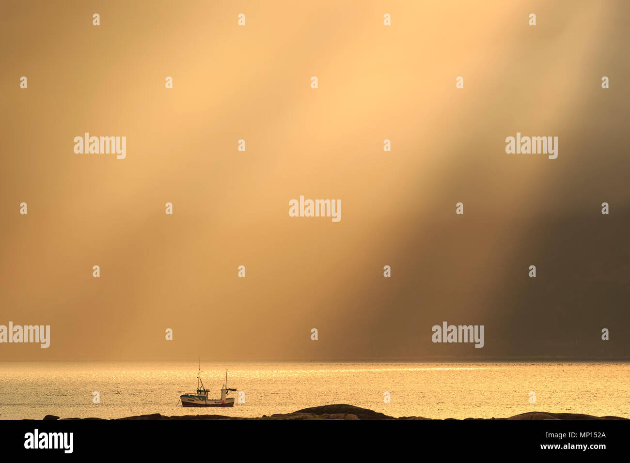 Golden sunrays over Atlantic Ocean during late night sunset in summer; the water is orange in color and a distant ship passes by Stock Photo