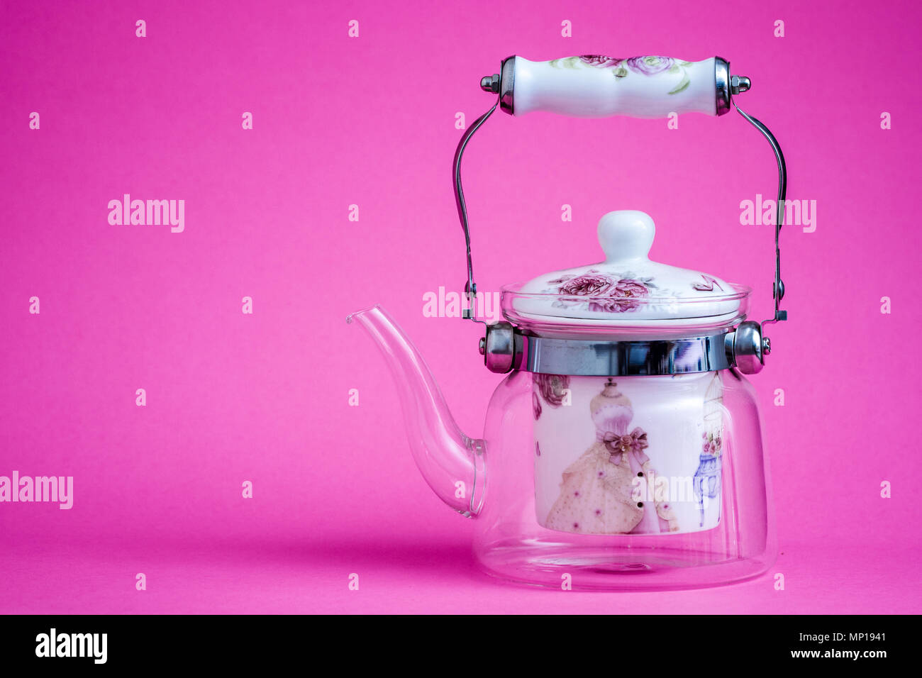 Heat resistant glass teapot with tea strainer on pink Stock Photo