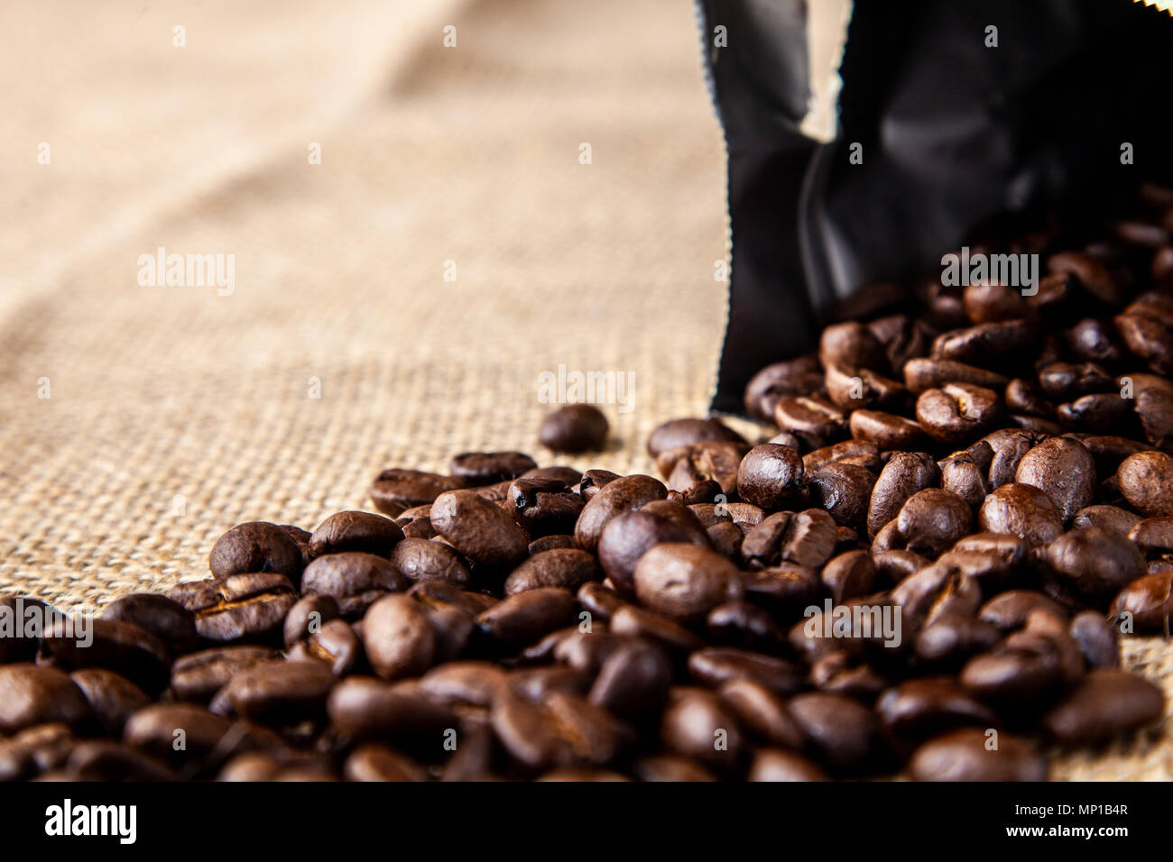Open bag of coffee beans spilled onto a jute cloth Stock Photo Alamy