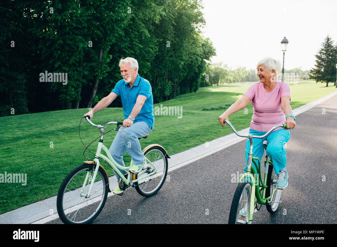 Mature happy couple riding bicycle laughing and getting joy from outdoor activities. Retired, active weekend on bicycles Stock Photo