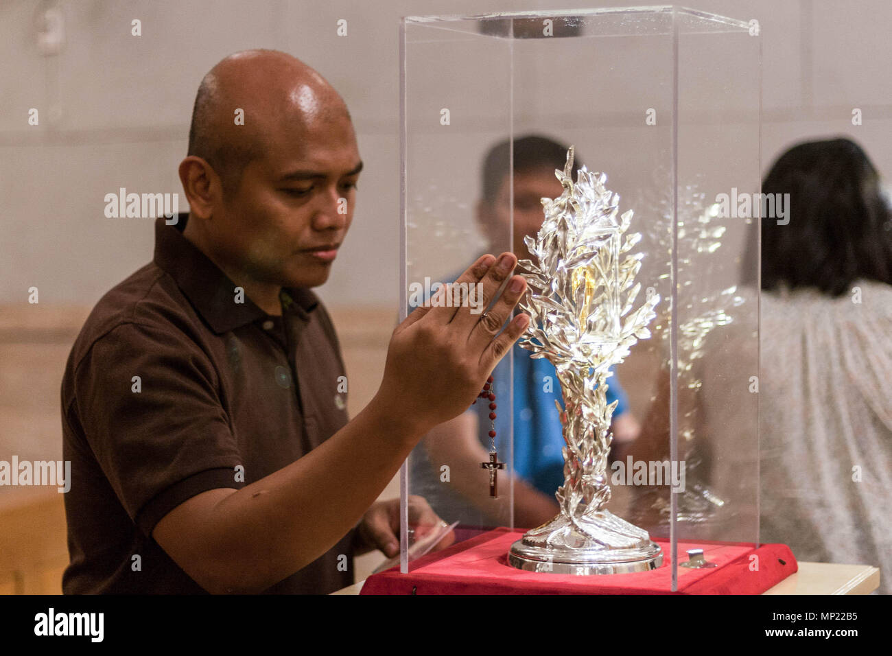 Manila, Philippines. 20th May 2018. A devotee prays as he touches the glass encasement of the blood reliquary. The Manila Cathedral in Intramuros displayed the blood relic of Pope John Paul II for public veneration. The blood was extracted from Pope John Paul II during his battle from Parkinson's disease, in case the Pope needed an emergency transfusion. Credit: SOPA Images Limited/Alamy Live News Stock Photo