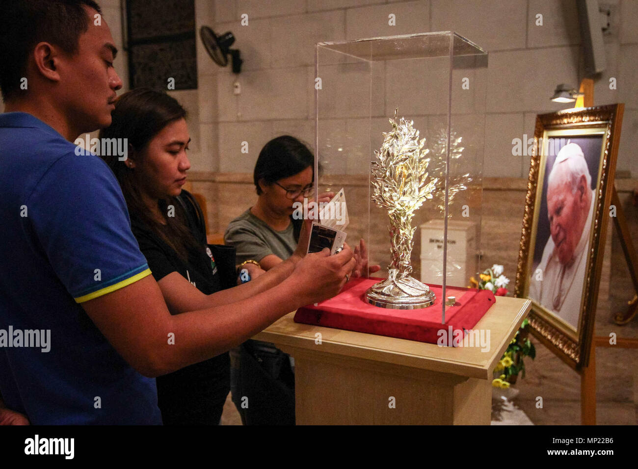 Manila, Philippines. 20th May 2018. Devotees pray as they touch the glass encasement of the blood reliquary. The Manila Cathedral in Intramuros displayed the blood relic of Pope John Paul II for public veneration. The blood was extracted from Pope John Paul II during his battle from Parkinson's disease, in case the Pope needed an emergency transfusion. Credit: SOPA Images Limited/Alamy Live News Stock Photo