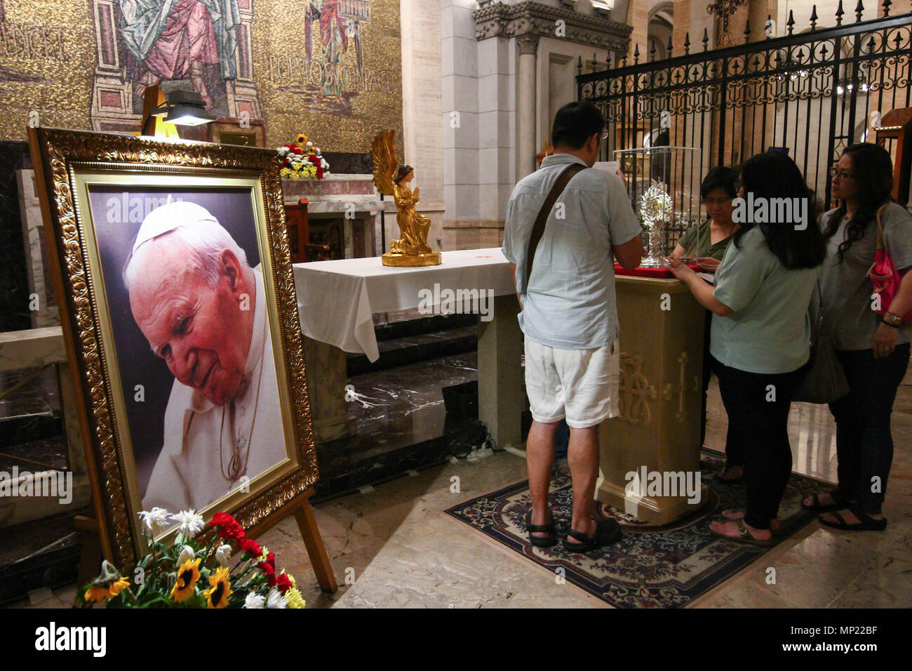 Manila, Philippines. 20th May 2018. Devotees pray as they touch the glass encasement of the blood reliquary. The Manila Cathedral in Intramuros displayed the blood relic of Pope John Paul II for public veneration. The blood was extracted from Pope John Paul II during his battle from Parkinson's disease, in case the Pope needed an emergency transfusion. Credit: SOPA Images Limited/Alamy Live News Stock Photo