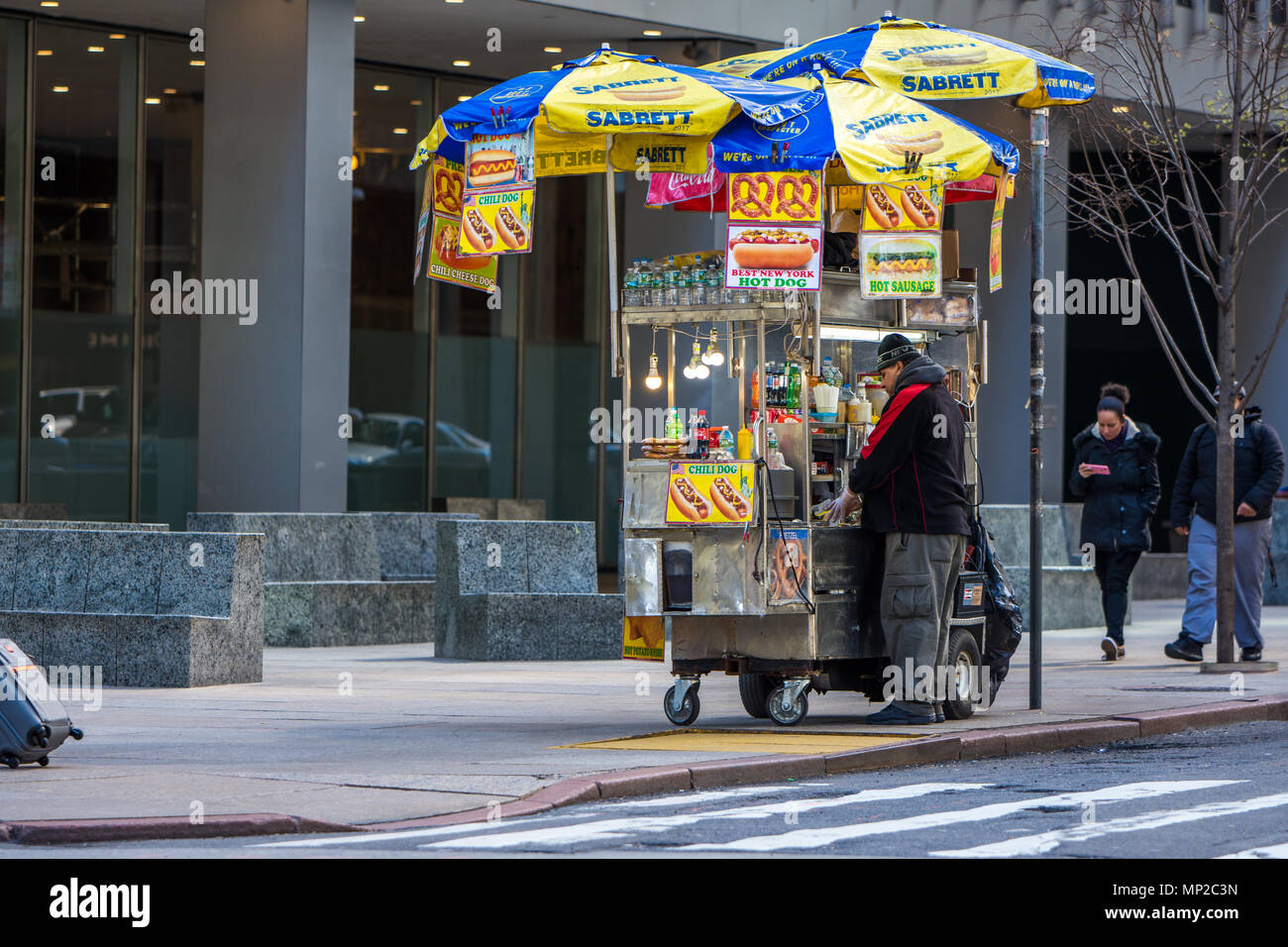 new York, US - March 31, 2018: Man selling street food and hot dofs in midtown Manhattan in New York city on a sunny day Stock Photo